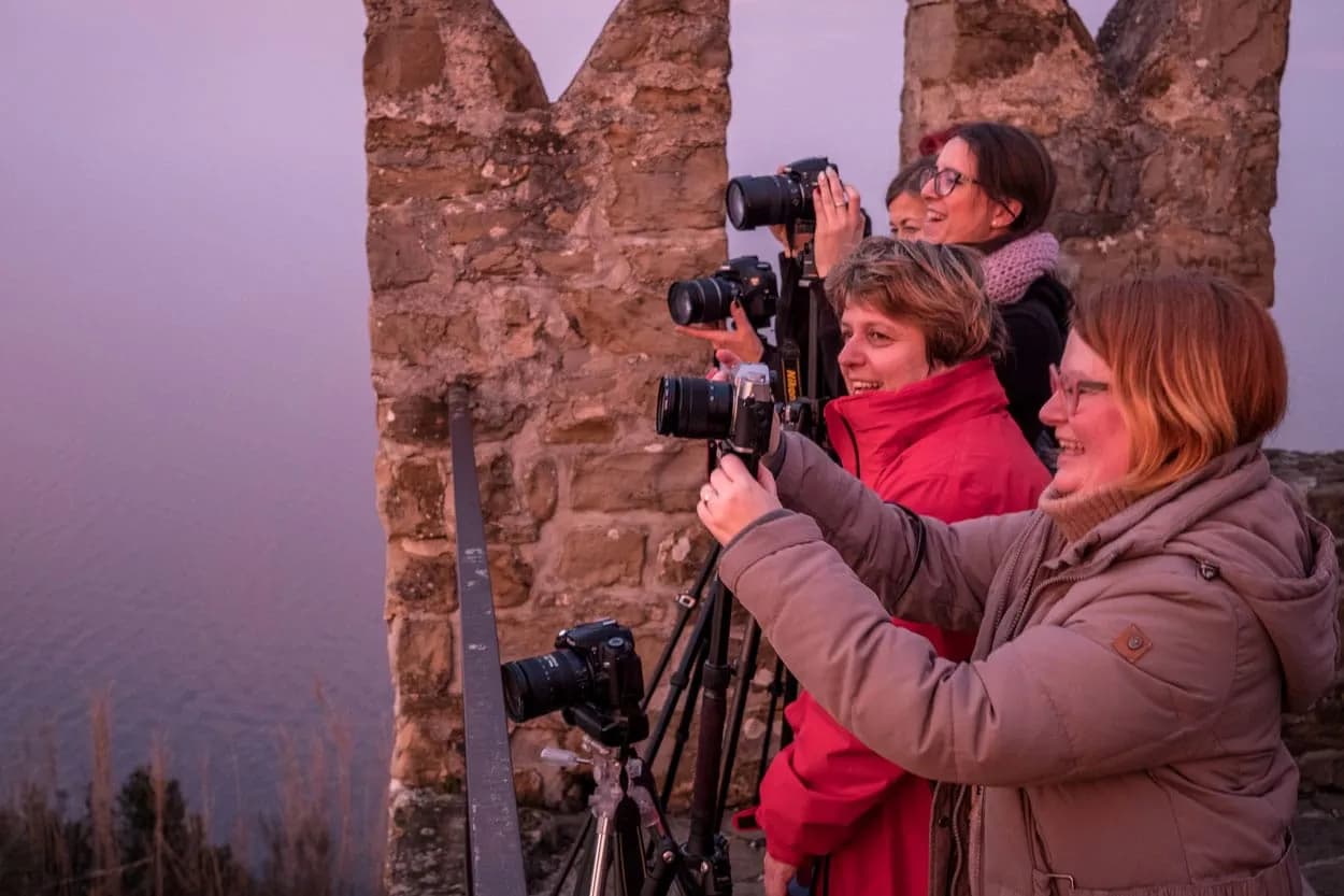 Group photographing sunset over water from stone battlement in Slovenia