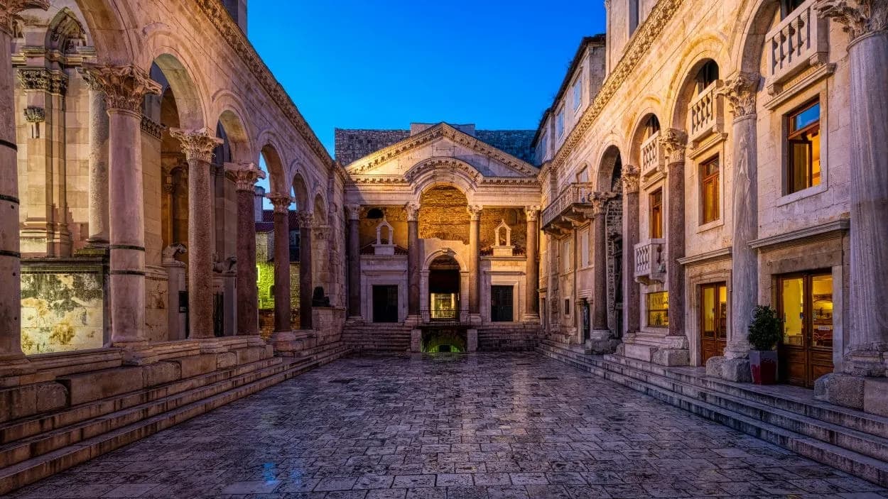 Stone courtyard of Roman palace ruins with columns and arches at twilight