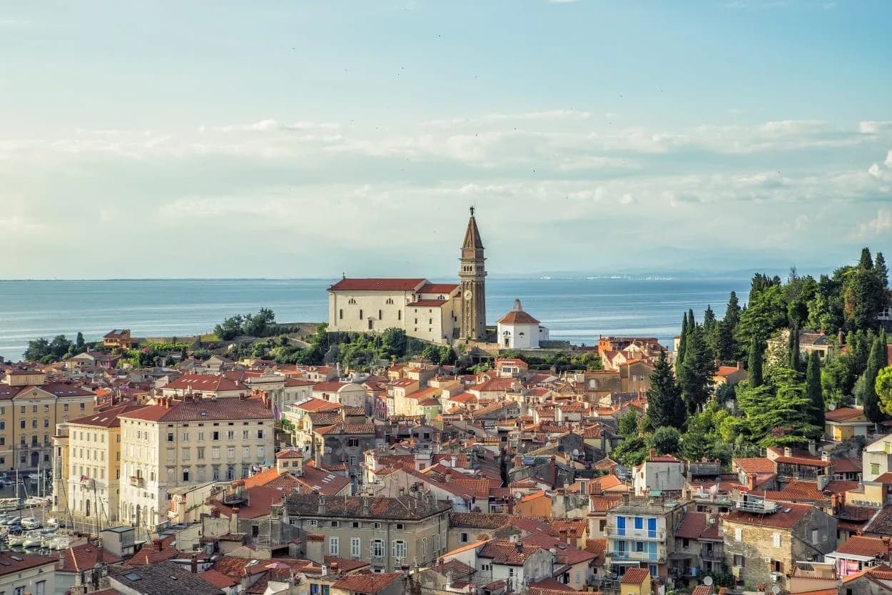 Coastal town of Piran with terracotta roofs, church tower, and the Adriatic Sea.
