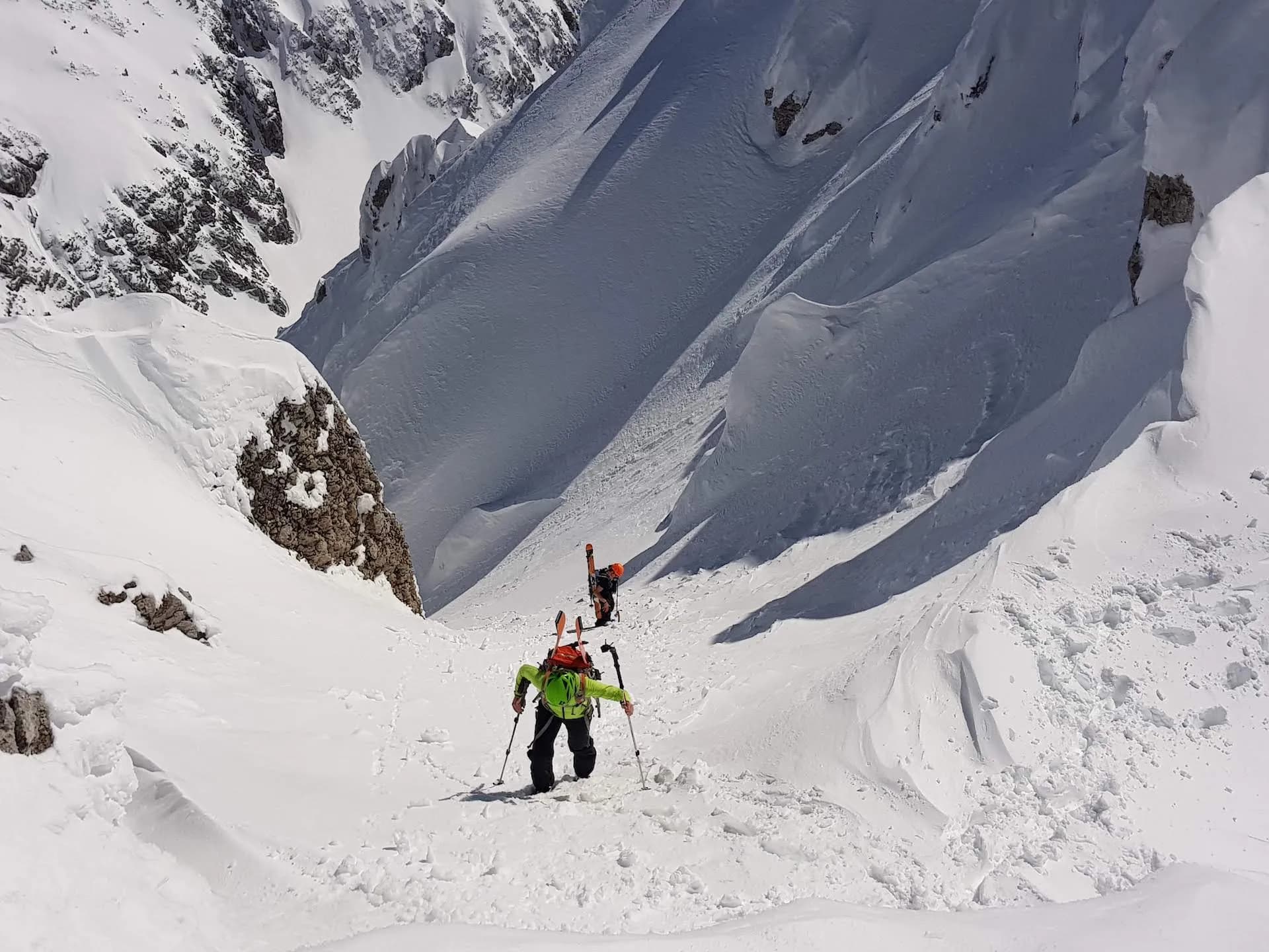 Ski mountaineers climbing a steep, snow-covered gully above Zelenica in winter.