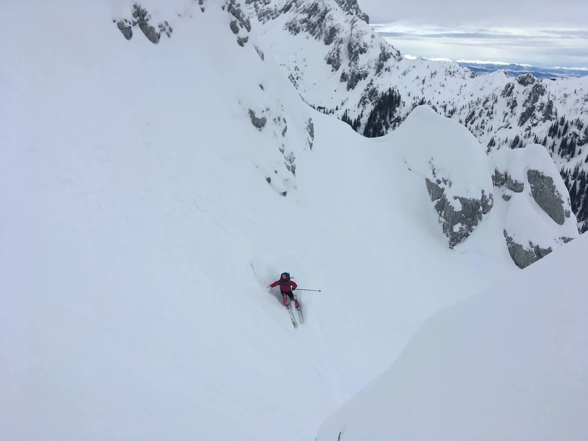 Steep skiing down a deep powder slope from Begunjščica mountain in winter.