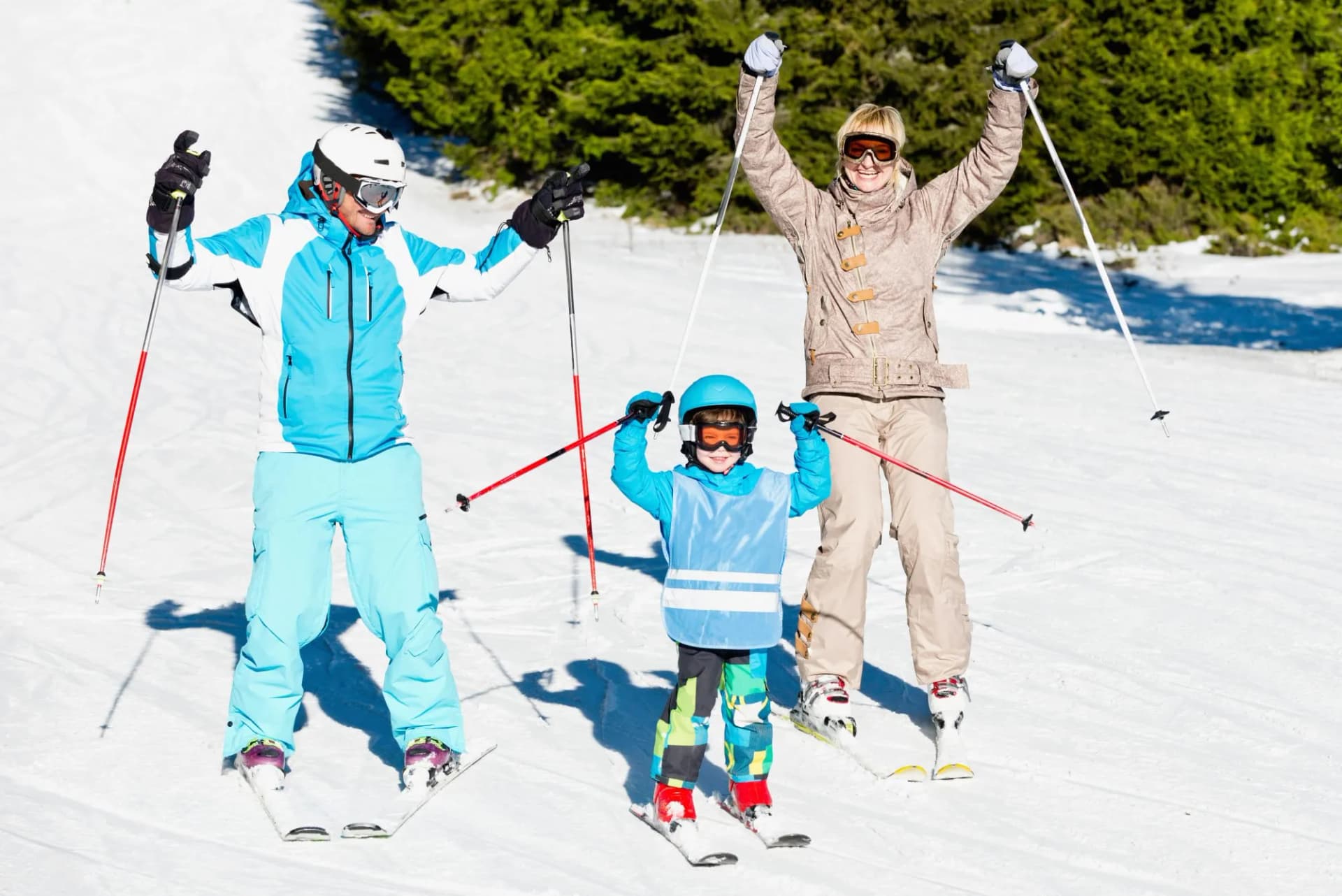 Family skiing on sunny slope with evergreen trees in the background
