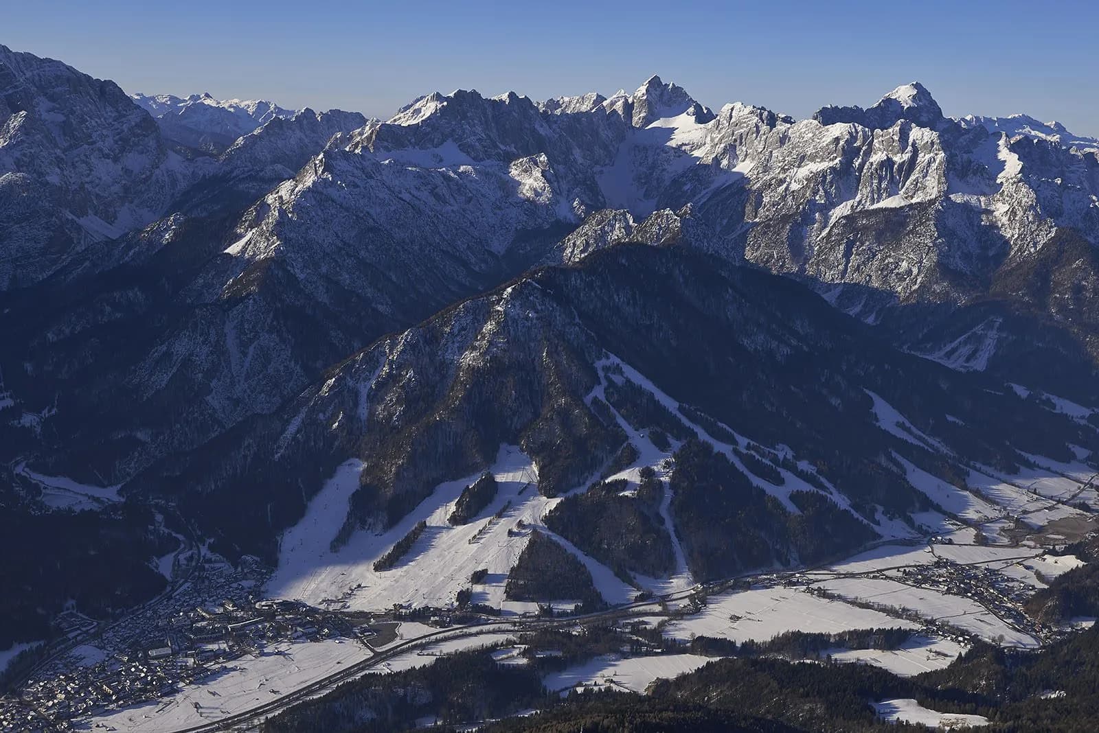 Snowy mountains towering over Kranjska Gora valley and ski slopes in winter
