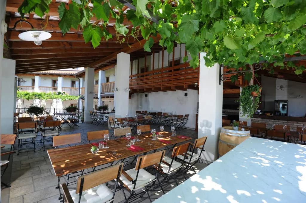 Outdoor restaurant seating under a vine-covered pergola at Belica Restaurant in Goriška Brda.