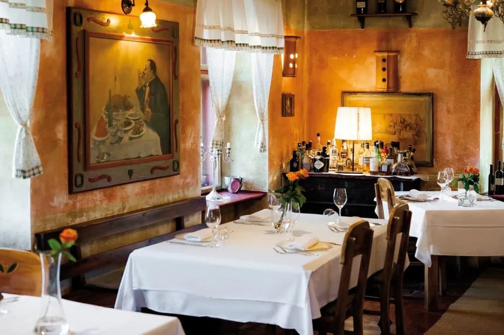 Dining room interior with white tablecloths, wooden chairs, and orange textured walls.