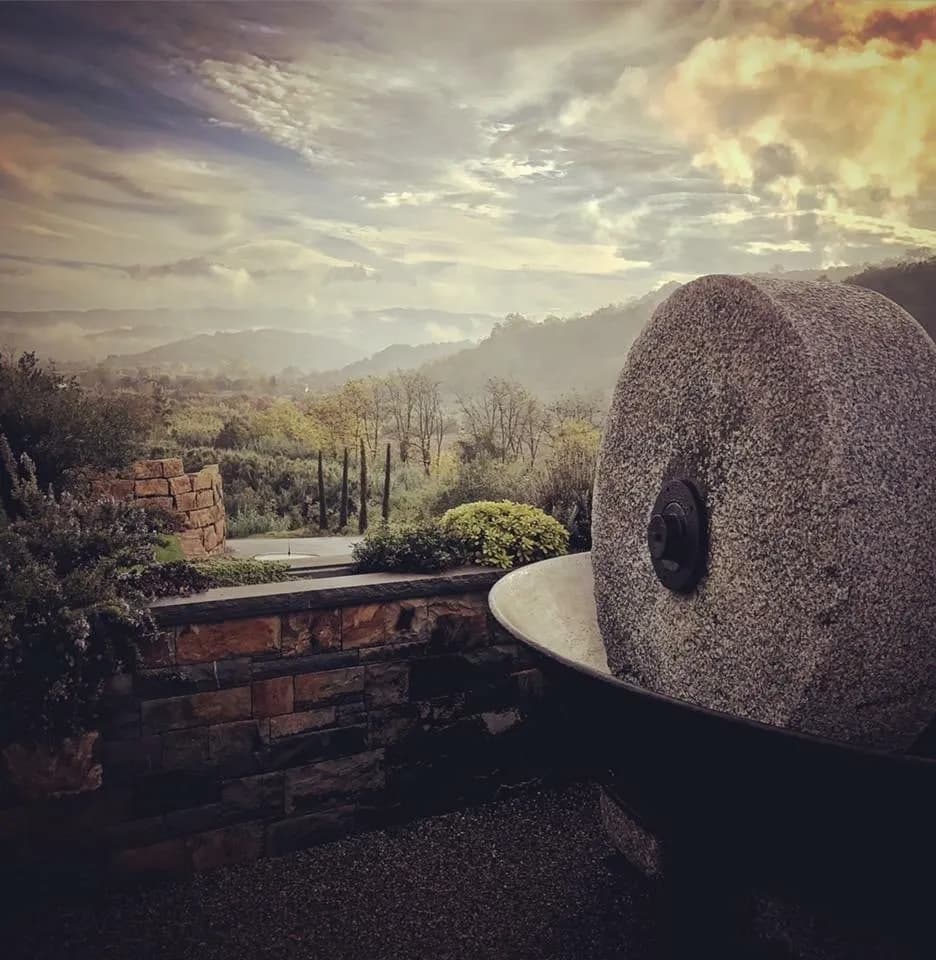 Stone mill wheel feature overlooking misty rolling hills and valley landscape
