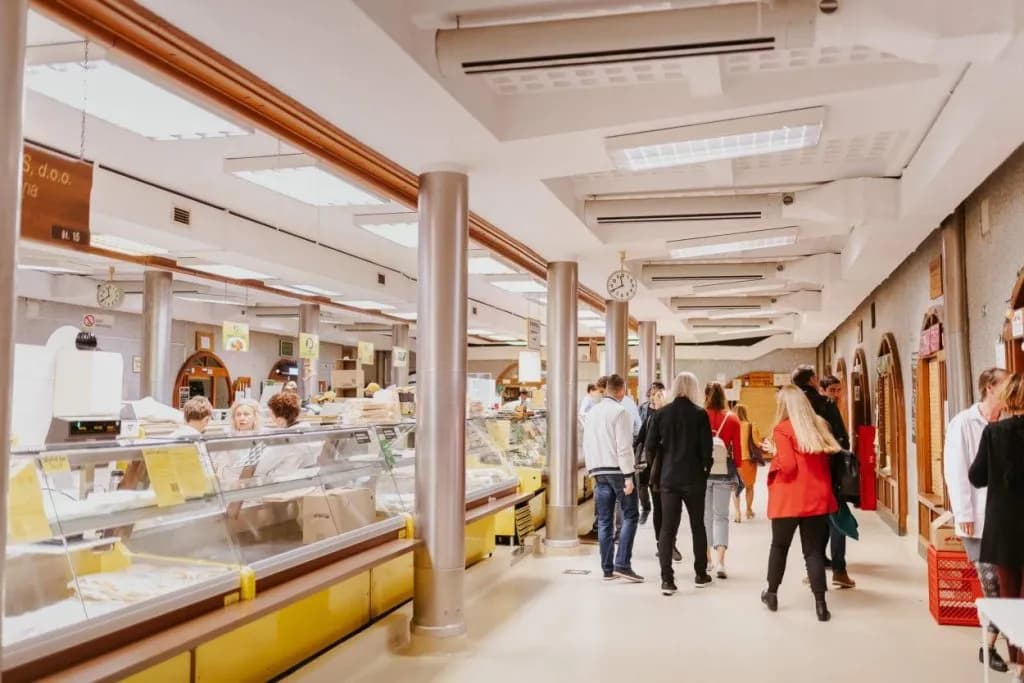 Shoppers browsing food stalls inside the Main Market in Ljubljana, Slovenia.