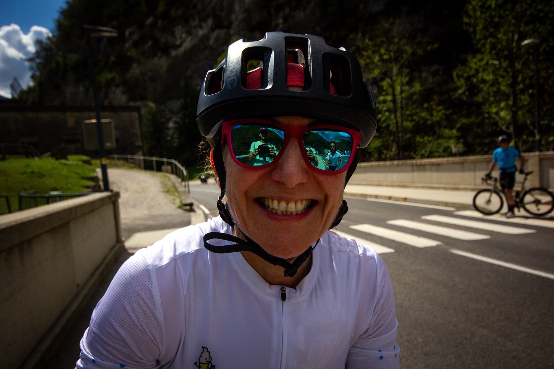 Cyclist smiling on road with dark trees and mountains in Soca Valley reflection