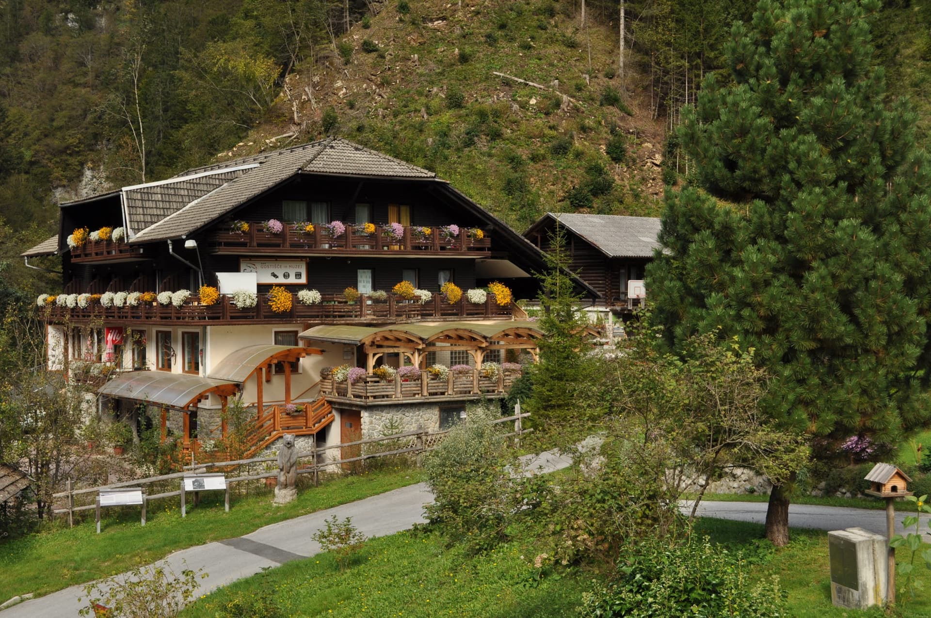 Gostišče Firšt inn with flower boxes on balconies against a forested mountain slope.