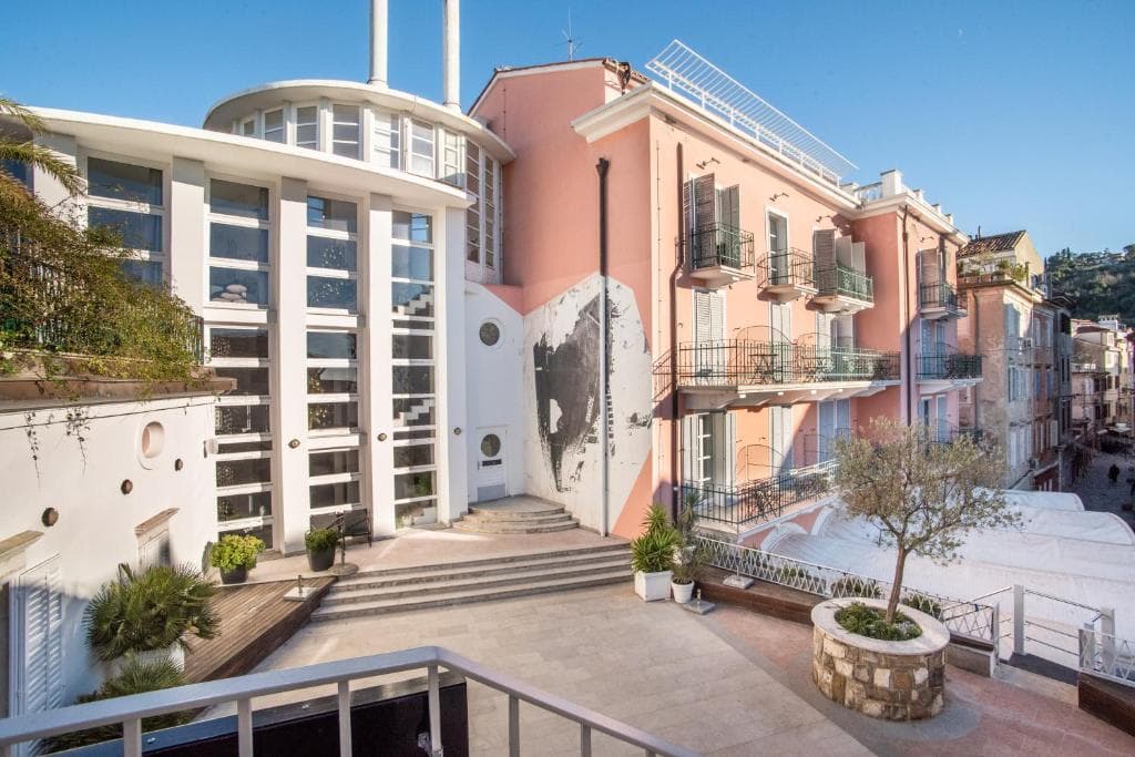 Hotel Tartini with modern white facade next to pink building in European coastal town.