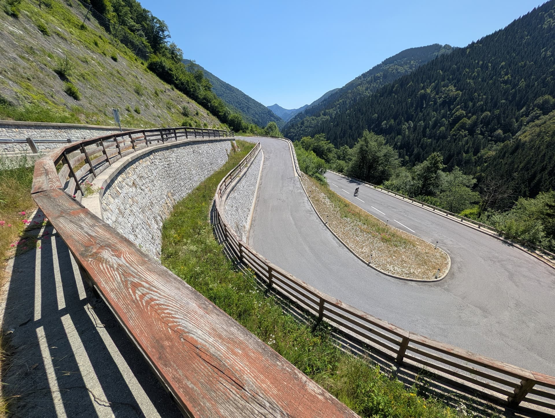 Hairpin bends on a winding mountain pass road with wooden guardrails