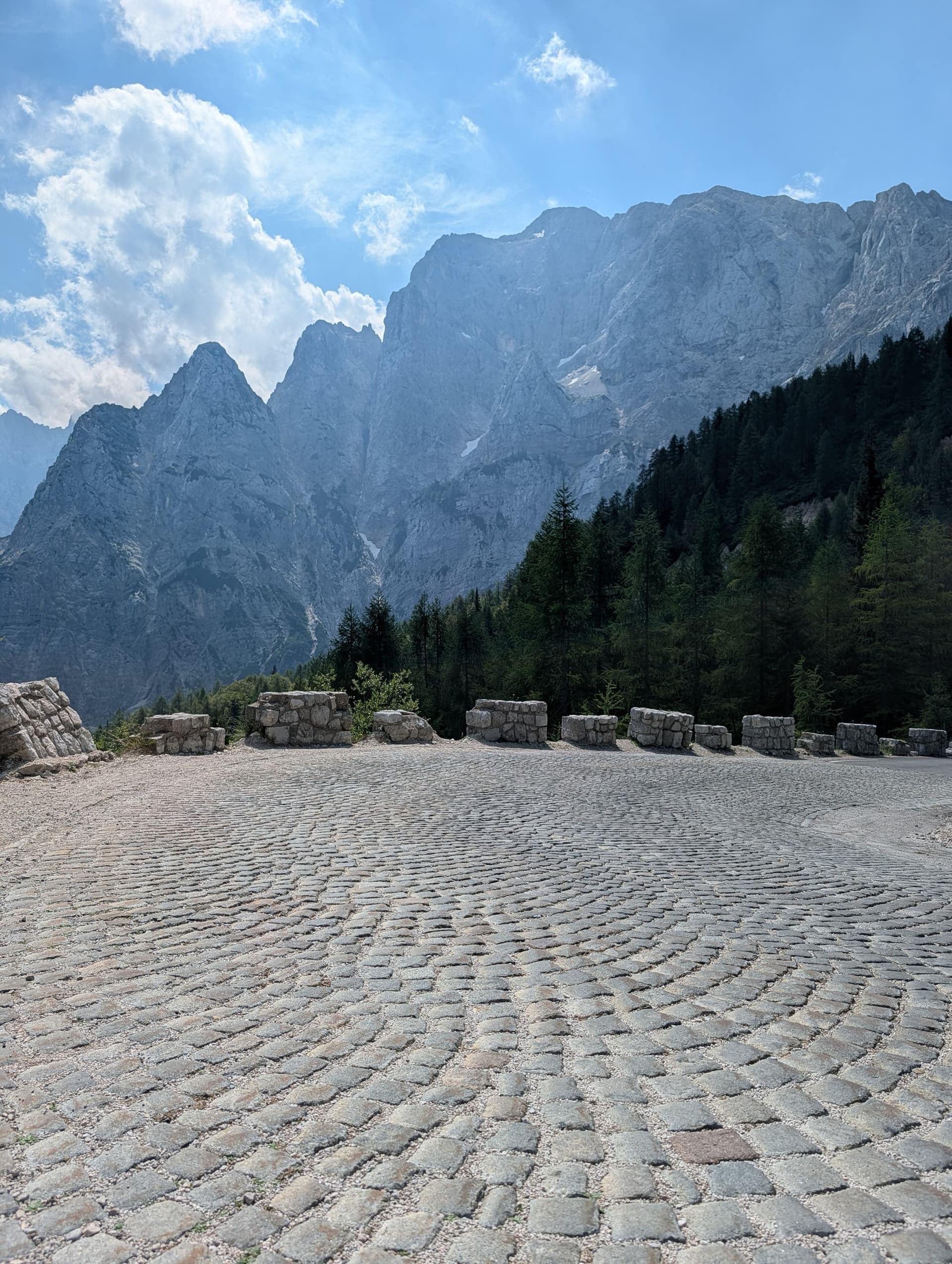 Cobblestone mountain pass with stone barriers below rocky limestone peaks