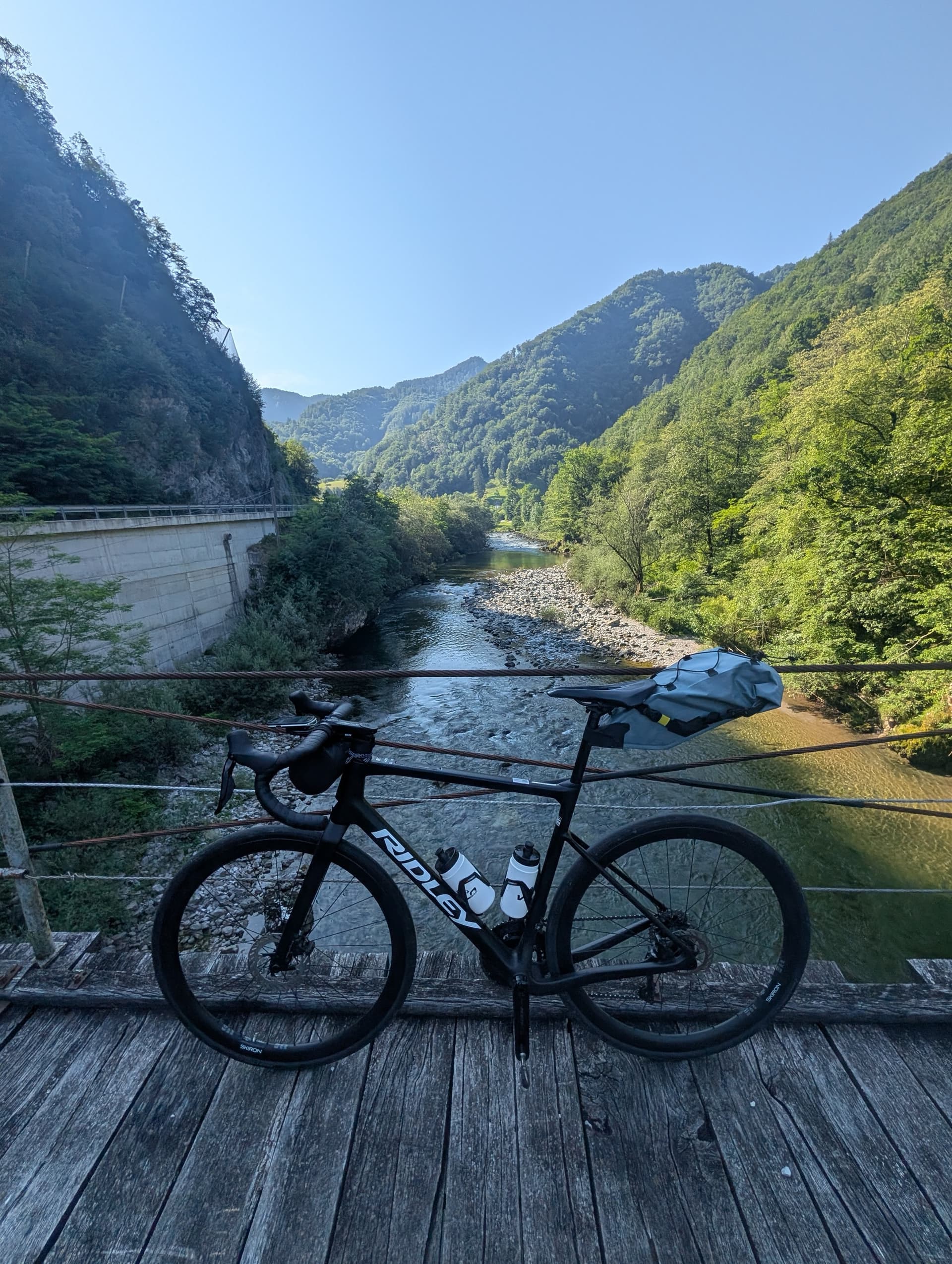 Road bike parked on wooden bridge overlooking mountain river valley