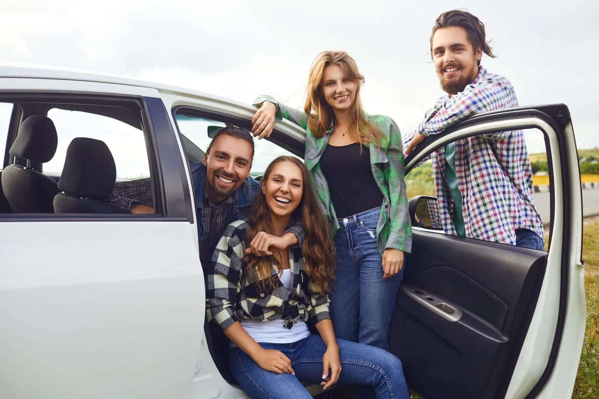 Two couples smiling while taking a break from a self-guided holiday next to a white car.