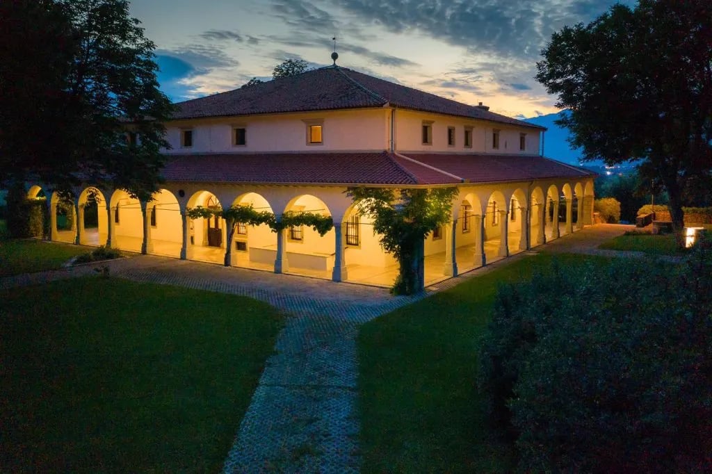 Illuminated villa with arched loggia and tiled roof at twilight, Dvorec Zemono.