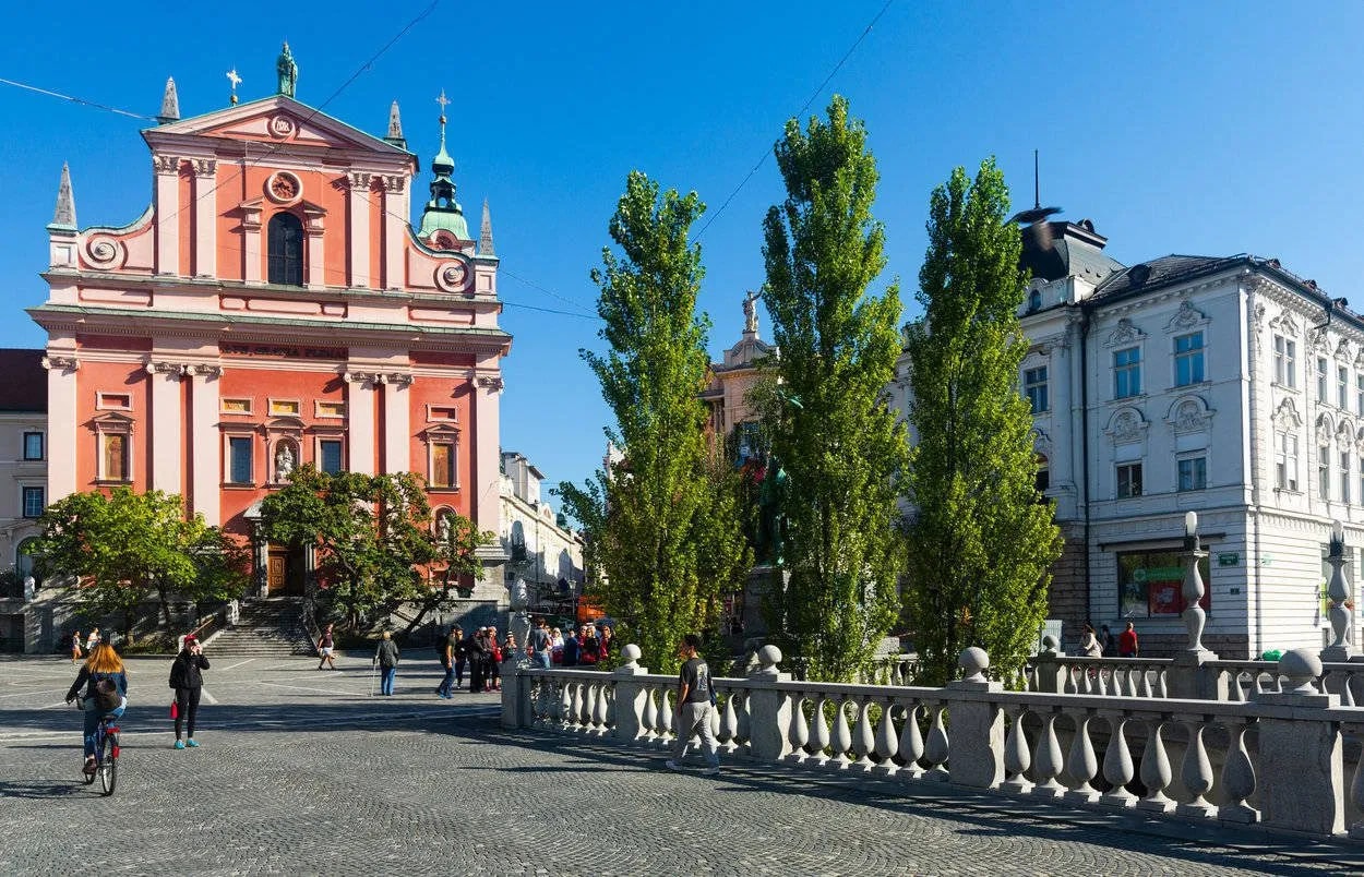 Preseren Square in Ljubljana with the pink Franciscan Church and people walking.