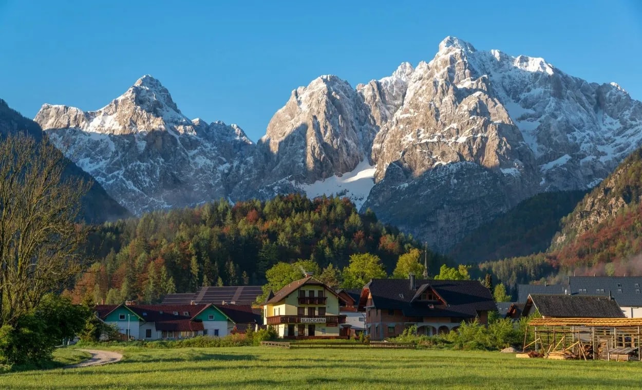 Kranjska Gora village houses below snow-capped Julian Alps mountains at sunrise