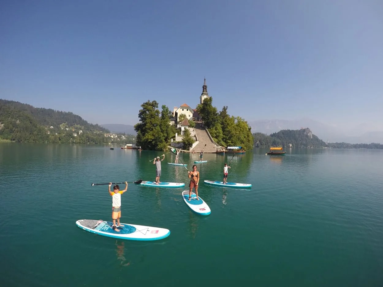 Standup paddle boarding on Lake Bled, Slovenia, with island church and mountains in background