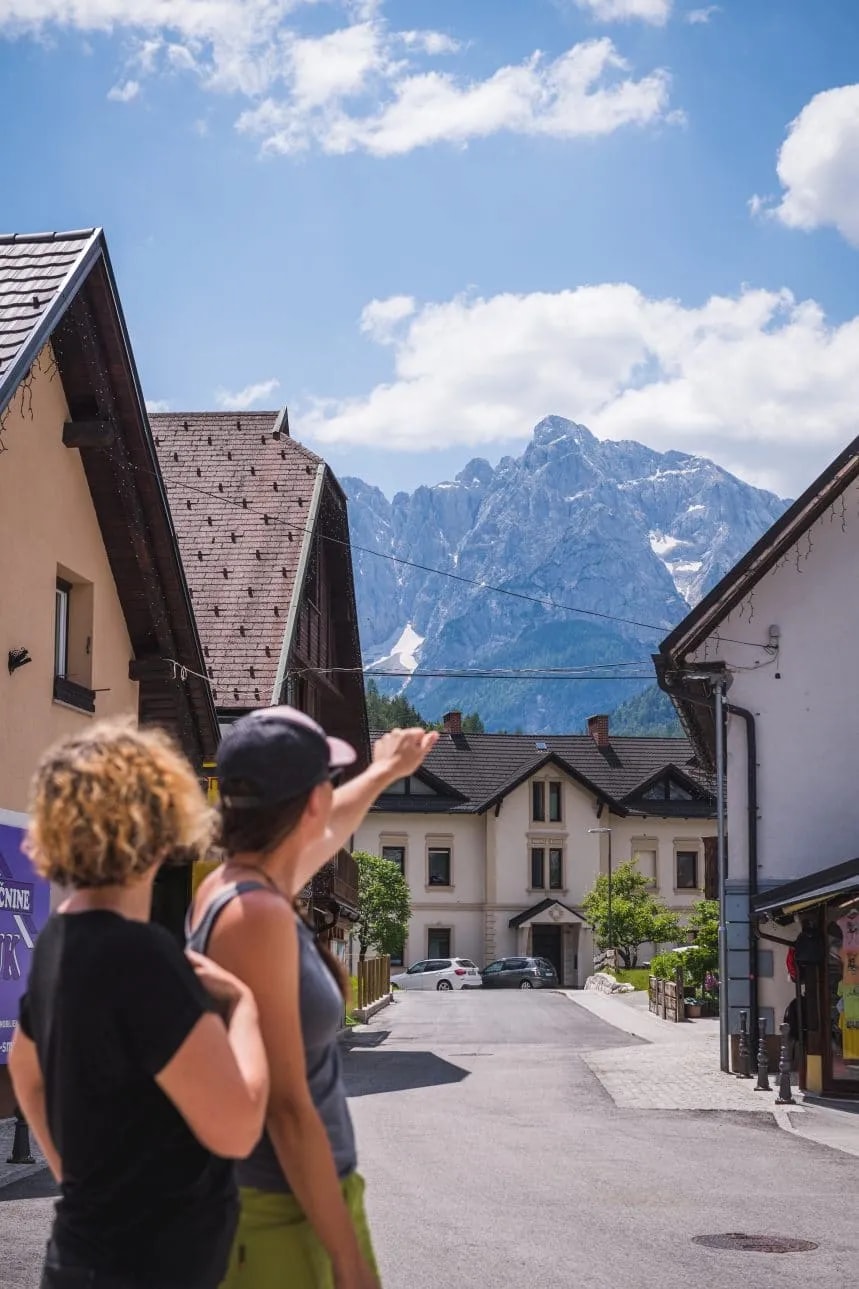Two people look toward snow-capped mountains from a street in Kranjska Gora, Slovenia.