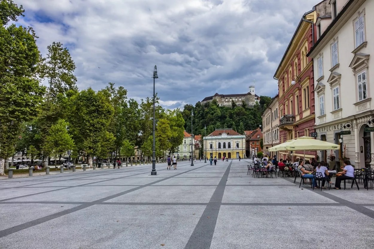 Kongresni trg square with outdoor cafe seating and Ljubljana Castle on a hill.