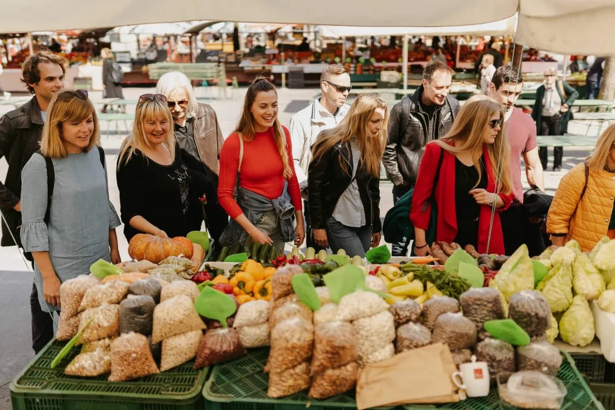Shoppers browsing fresh produce and bagged goods at the Central Market in Ljubljana.