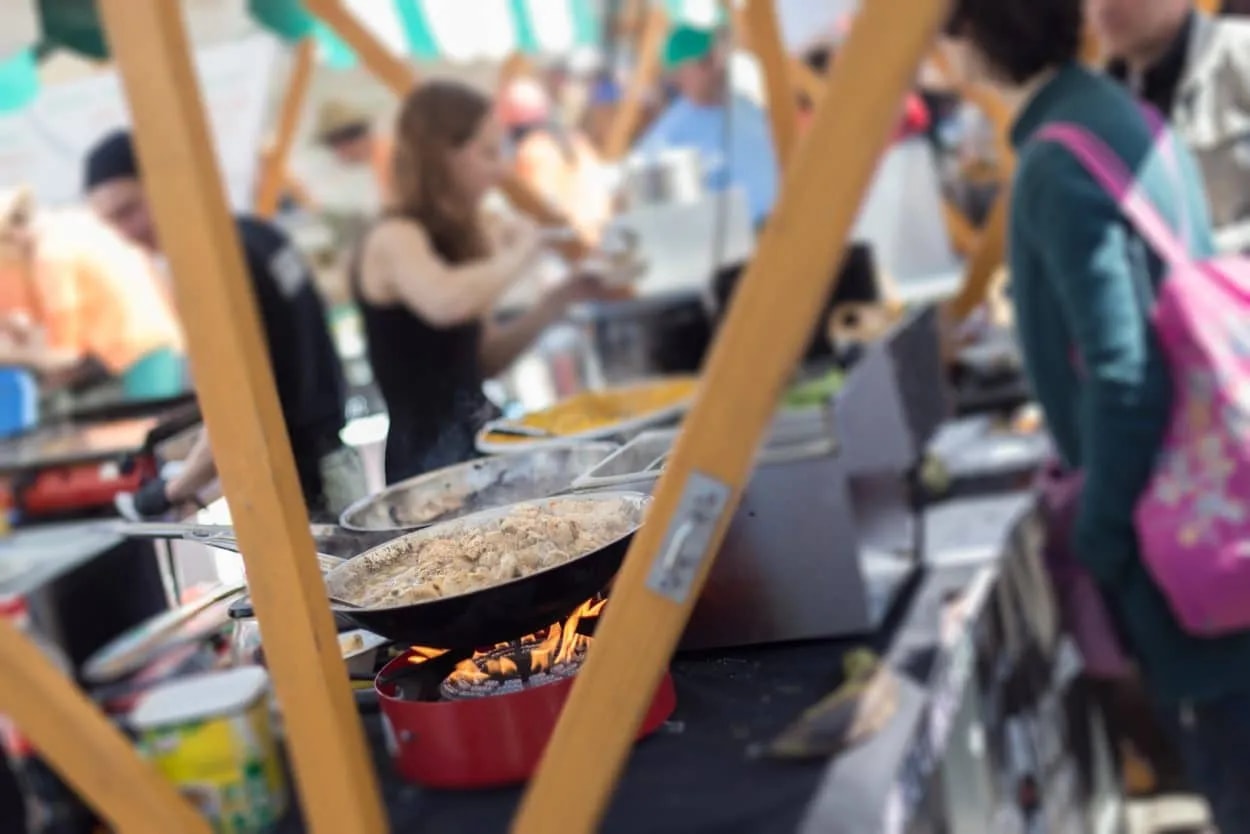 Food vendor cooking in pan over open flame at an outdoor market in Ljubljana