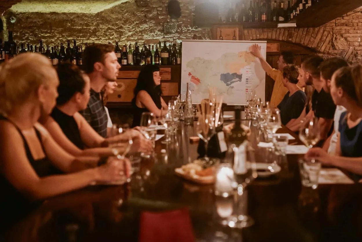 Wine tasting class in cellar with map presentation and wine bottles on stone wall