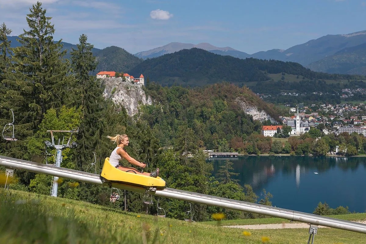 Woman on summer toboggan run overlooking Lake Bled and Bled Castle, Slovenia