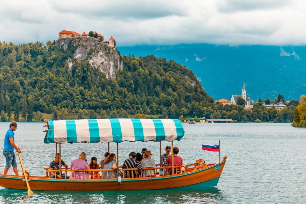 Pletna boat ride on Lake Bled with Bled Castle on a cliff in the background.