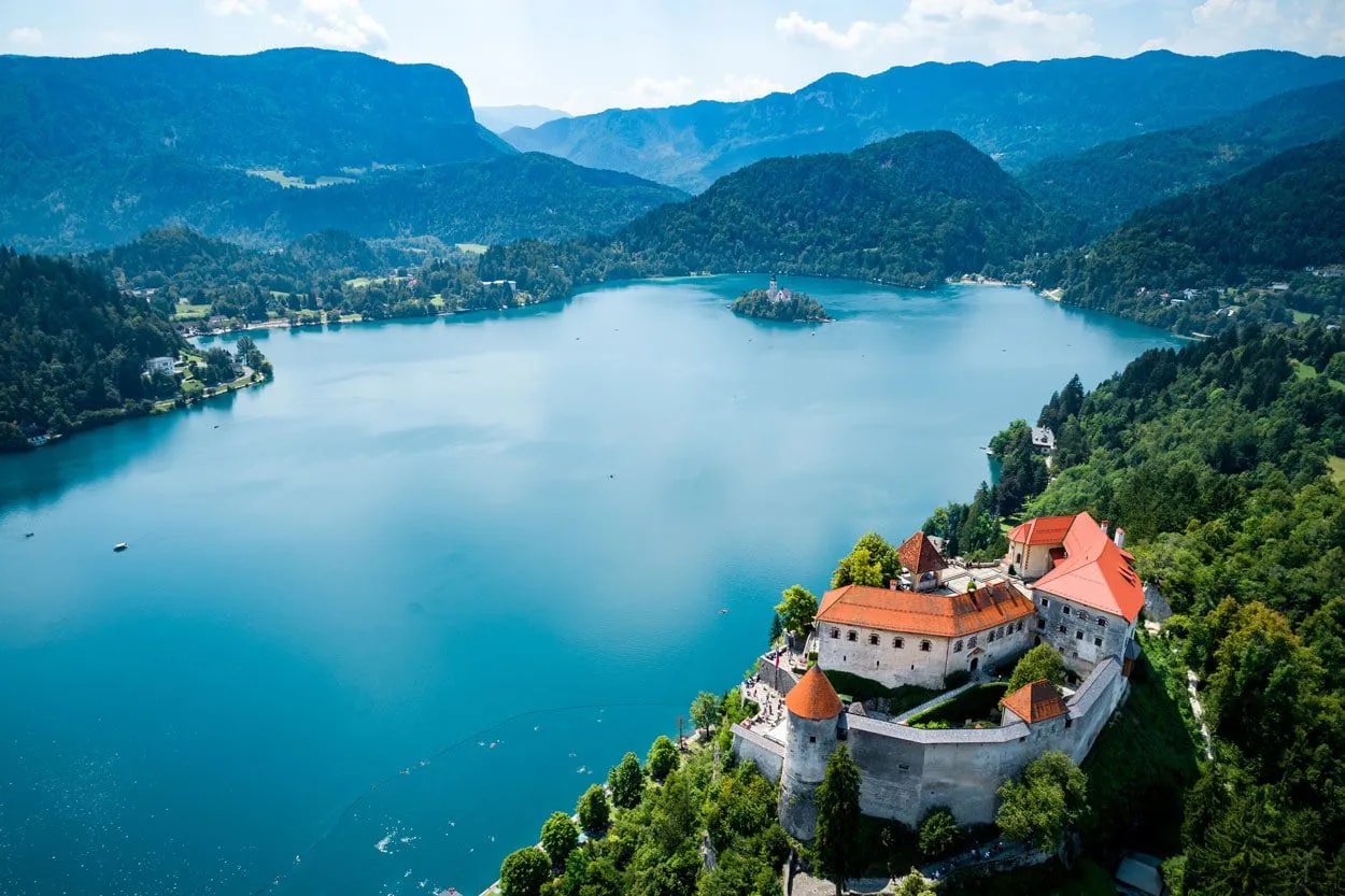 Lake Bled Castle overlooking bright blue water, island church, and surrounding mountains in Slovenia.