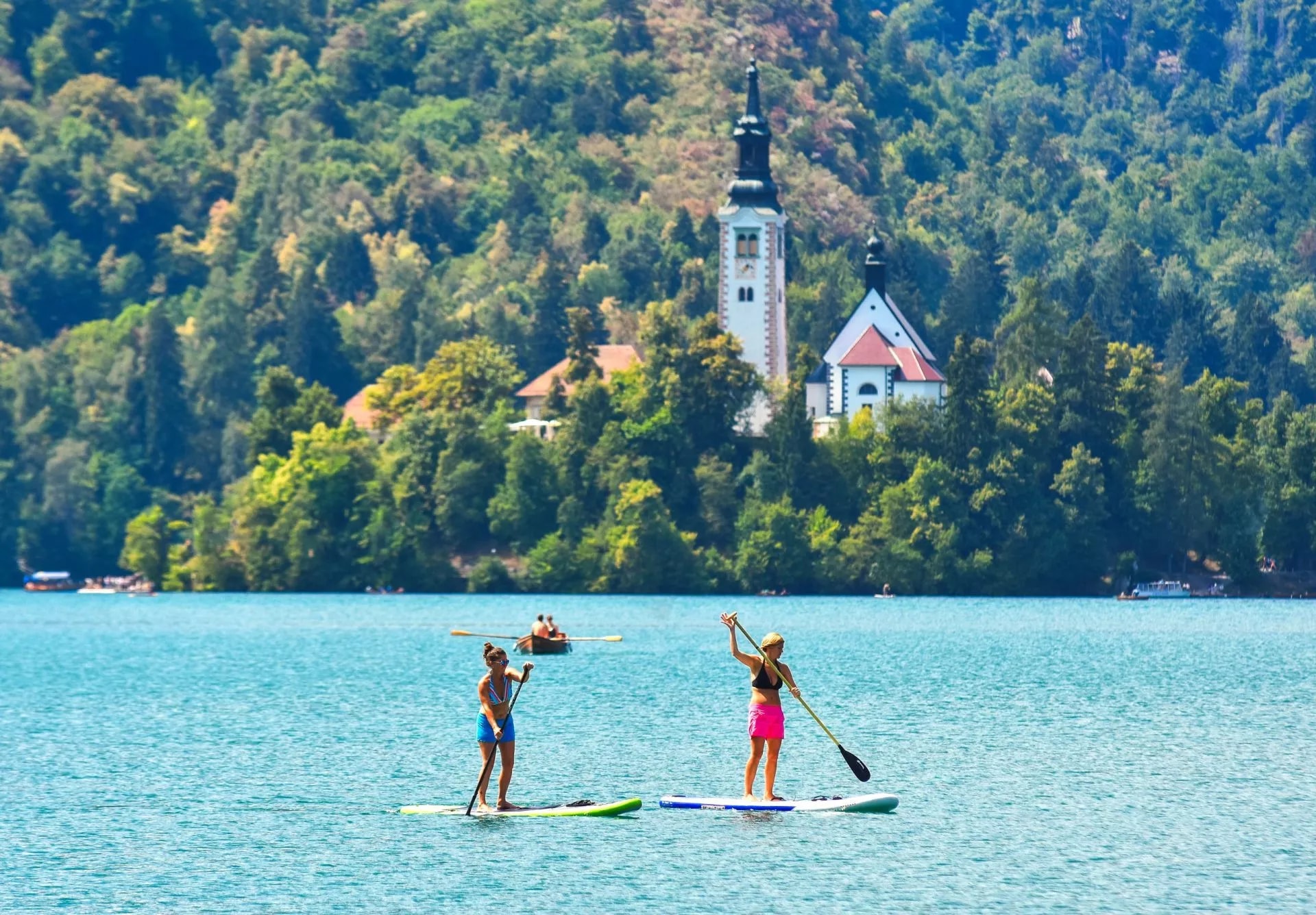 Paddleboarding on Lake Bled with the island church visible on the wooded shore.