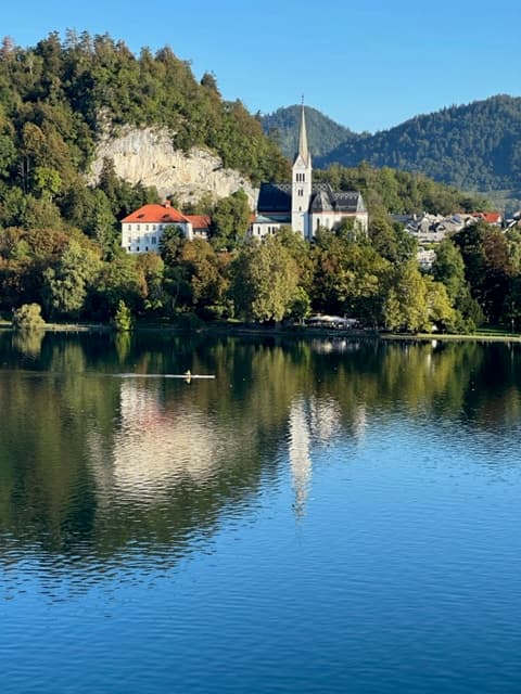 Rowboat on Lake Bled with church reflection and forested hills in Slovenia