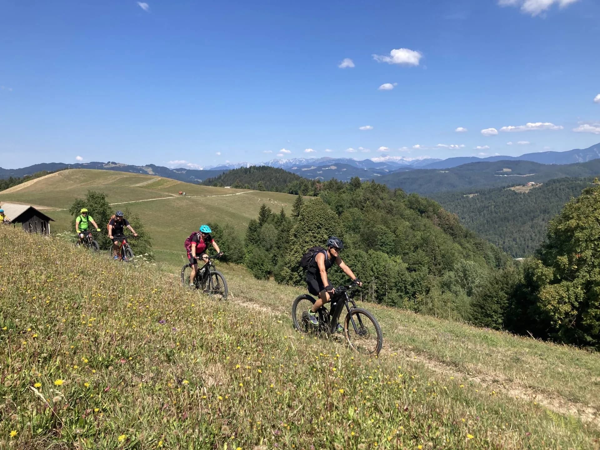 Mountain bikers cycling along a grassy ridge overlooking hills near Ziri town.