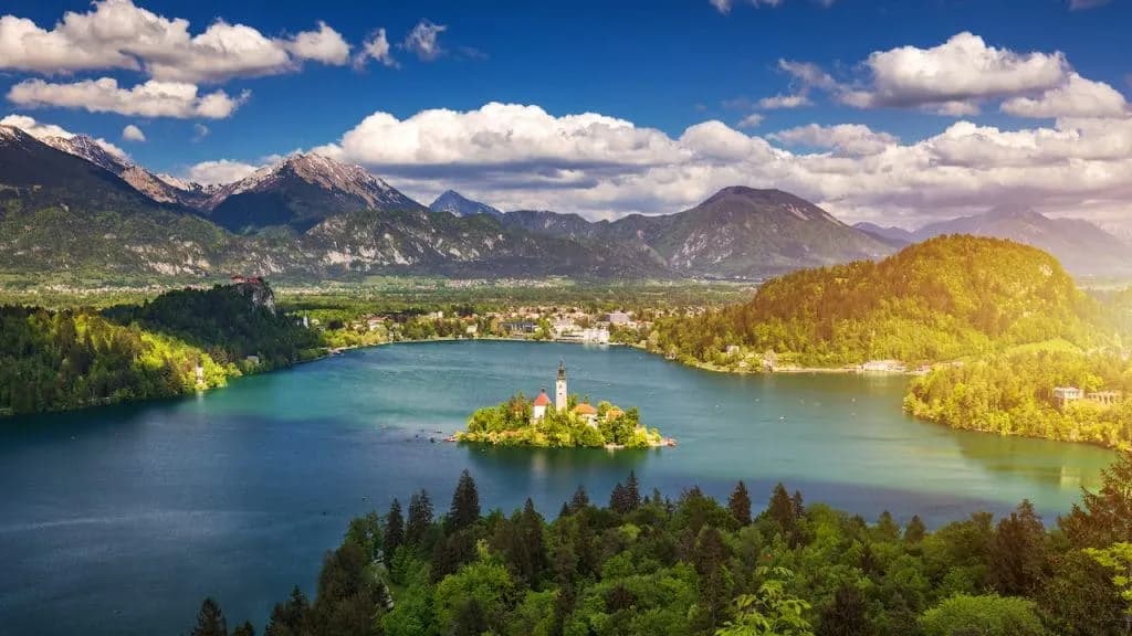 Panoramic view of Lake Bled island church with Julian Alps and bright blue sky