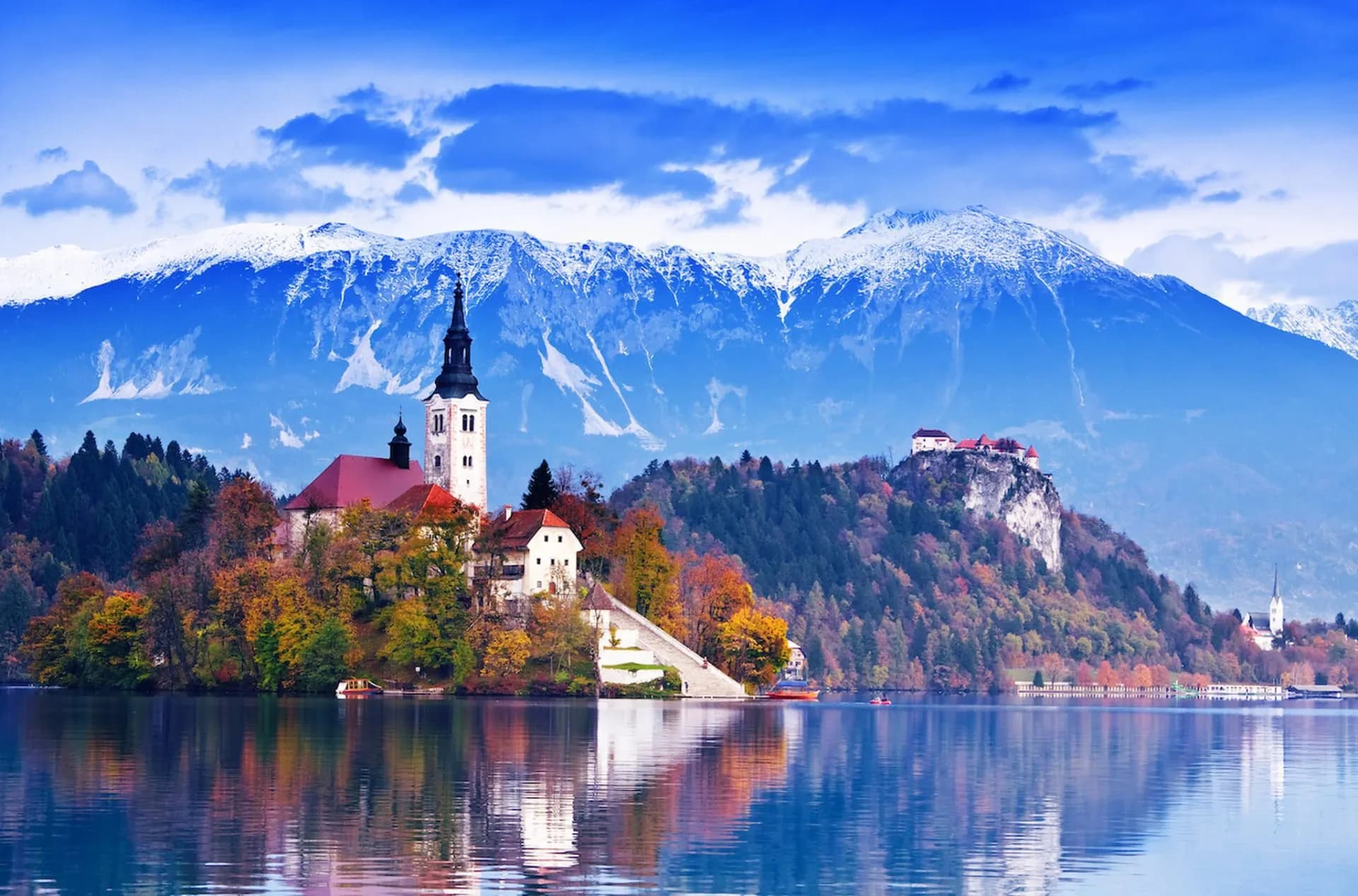Lake Bled island church and castle with snow-capped mountains and autumn trees