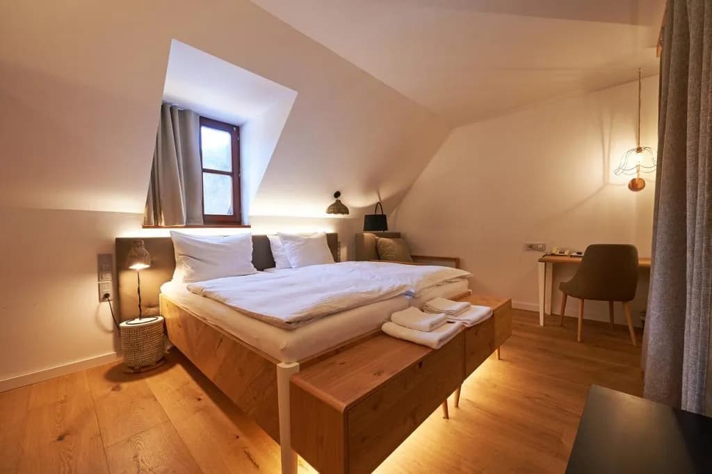 Hotel room with wooden bed, white linens, and sloped ceiling at Hotel Plesnik