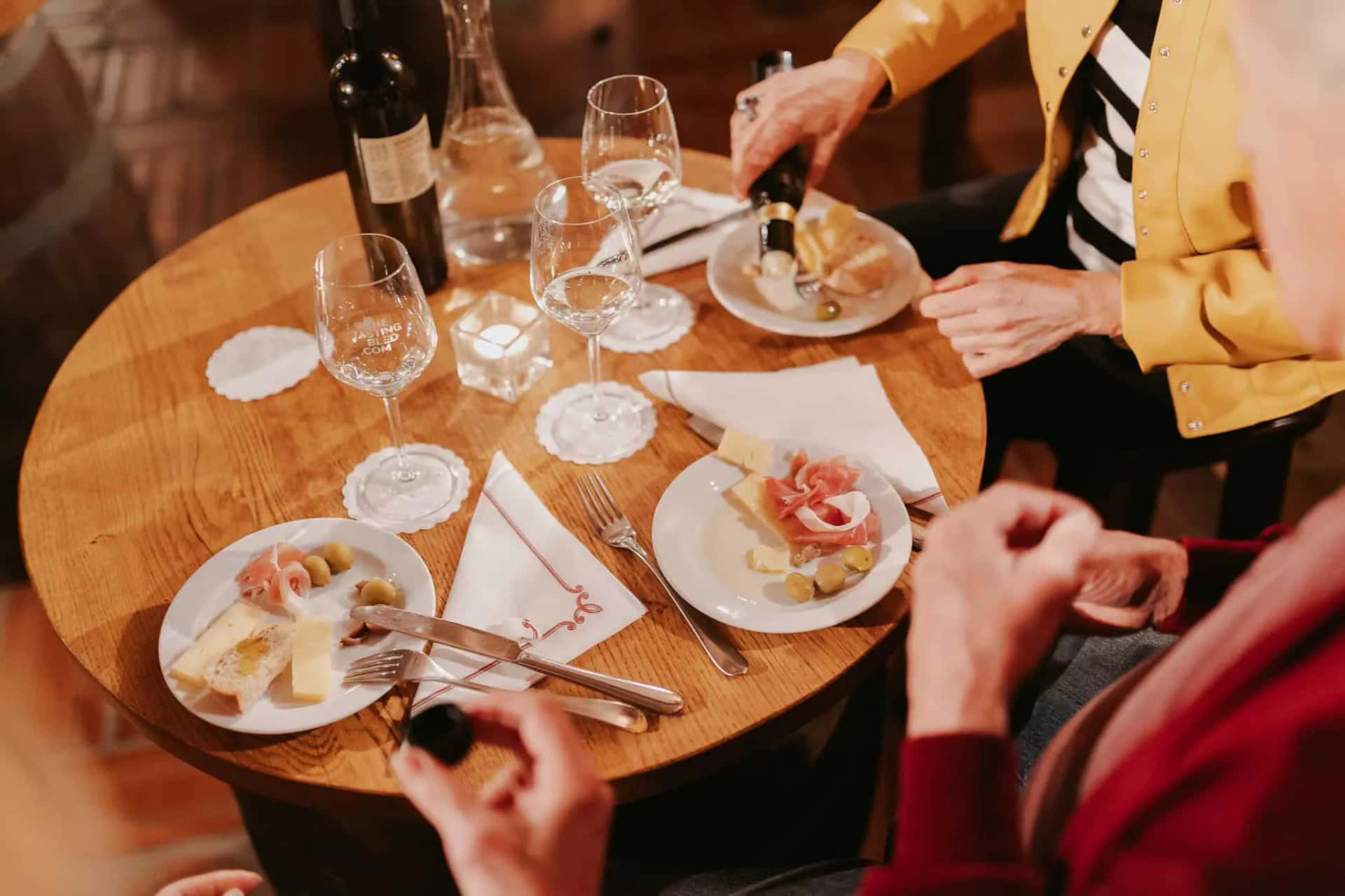Wine tasting with cheese, prosciutto, and olives on a wooden table in Slovenia.