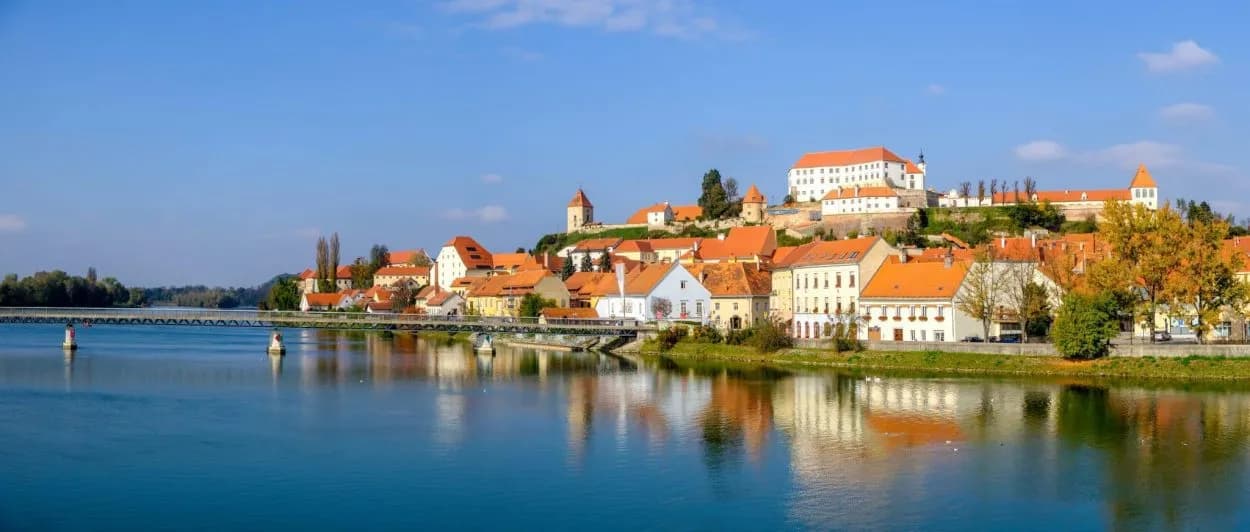 Townscape with orange roofs on a hill above a river, Ptuj, Slovenia.