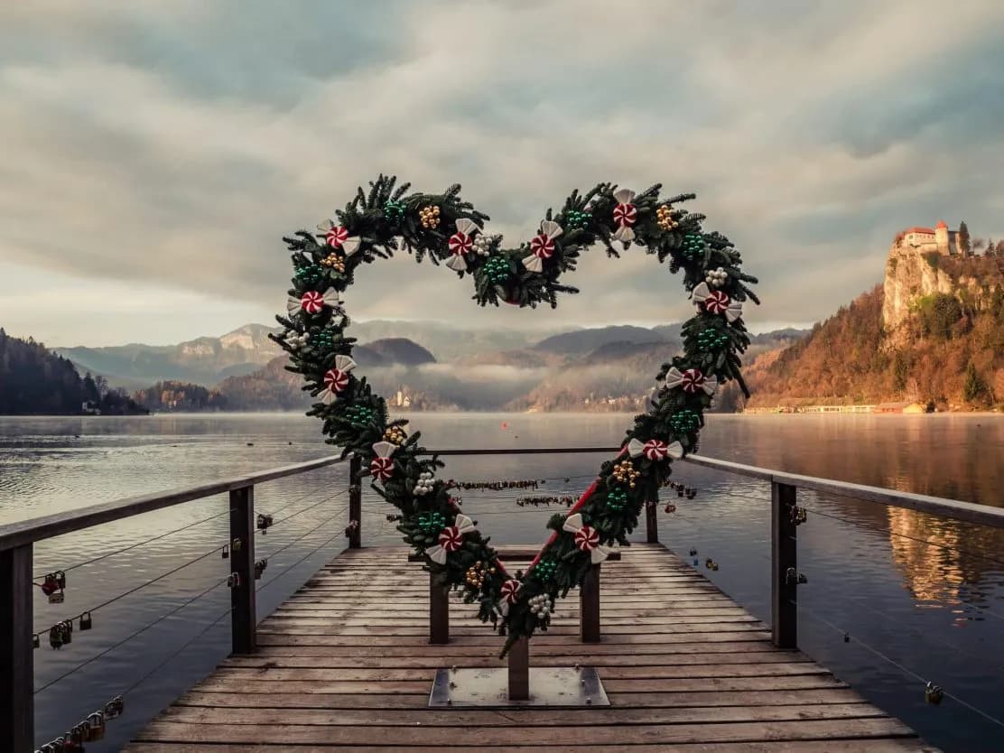 Heart-shaped wreath on dock overlooking Lake Bled with castle on cliff