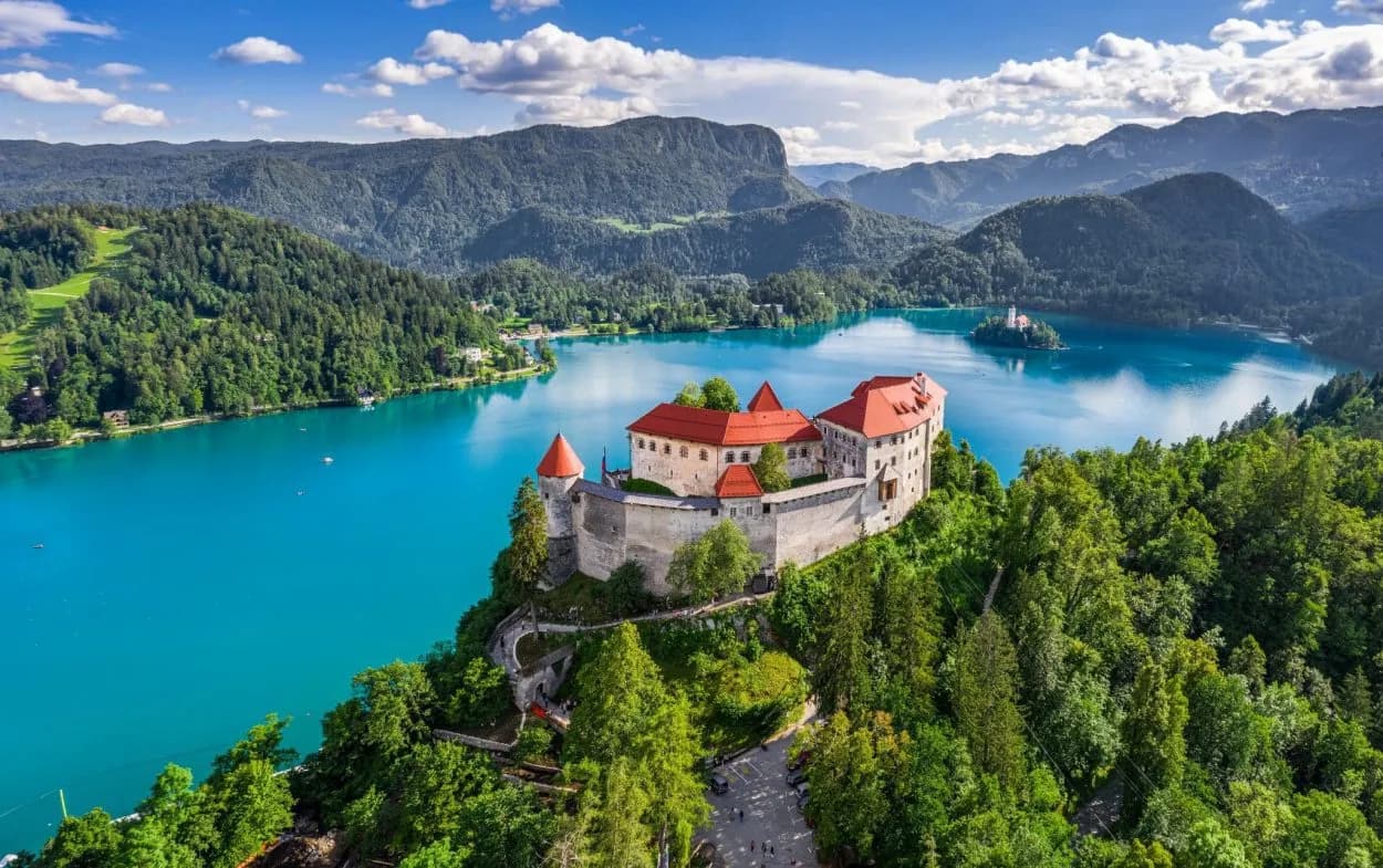 Bled Castle overlooking turquoise Lake Bled with island church and forested mountains.