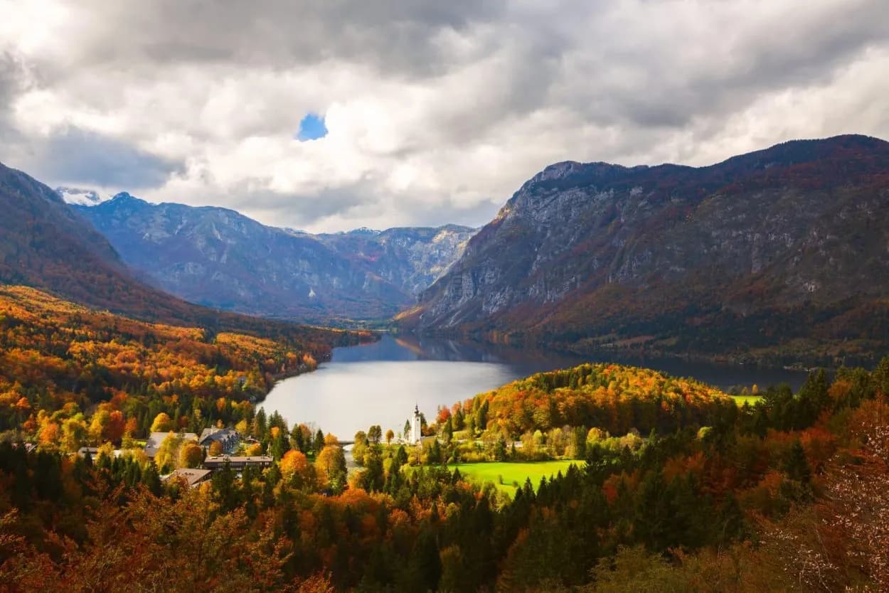 Lake Bohinj in Triglav National Park, Slovenia, with autumn foliage and mountains.