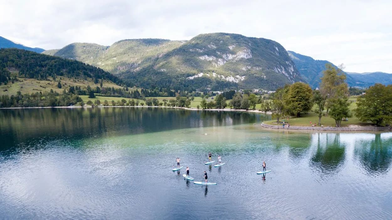 Paddleboarding on Lake Bohinj, Slovenia, with forested mountains reflecting in the water.