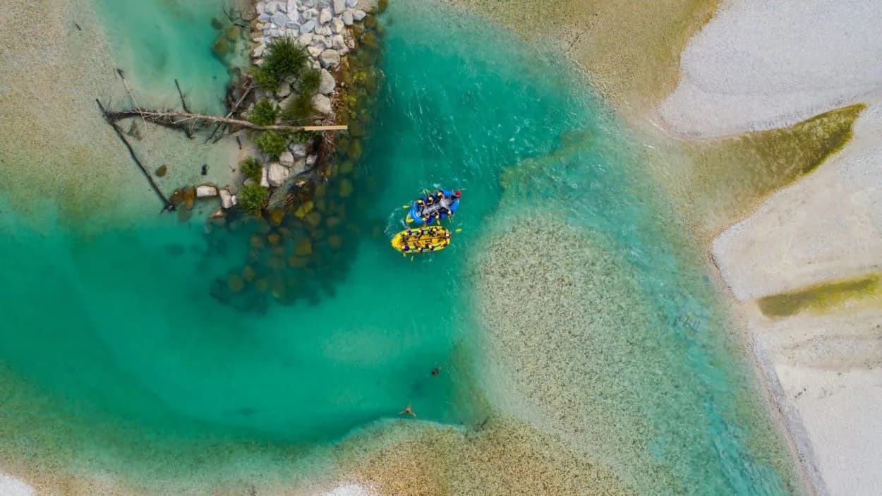 White-water rafting on turquoise Soca River with rocky banks, aerial view