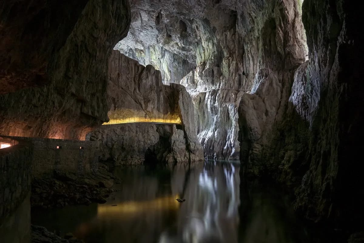 Underground river in Škocjan Caves with illuminated walkway along towering rock walls