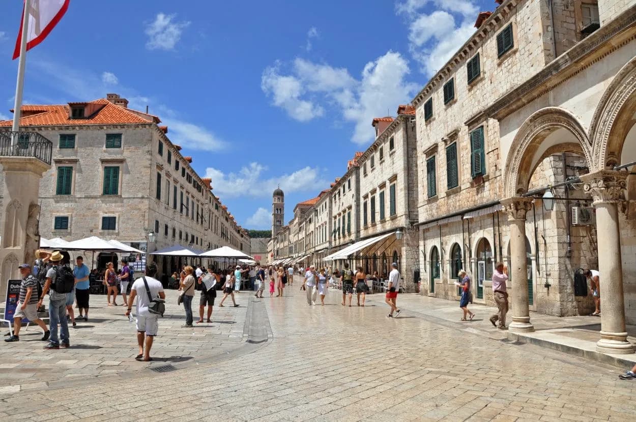 Pedestrians walking on the main stone street lined with historic buildings in Dubrovnik.