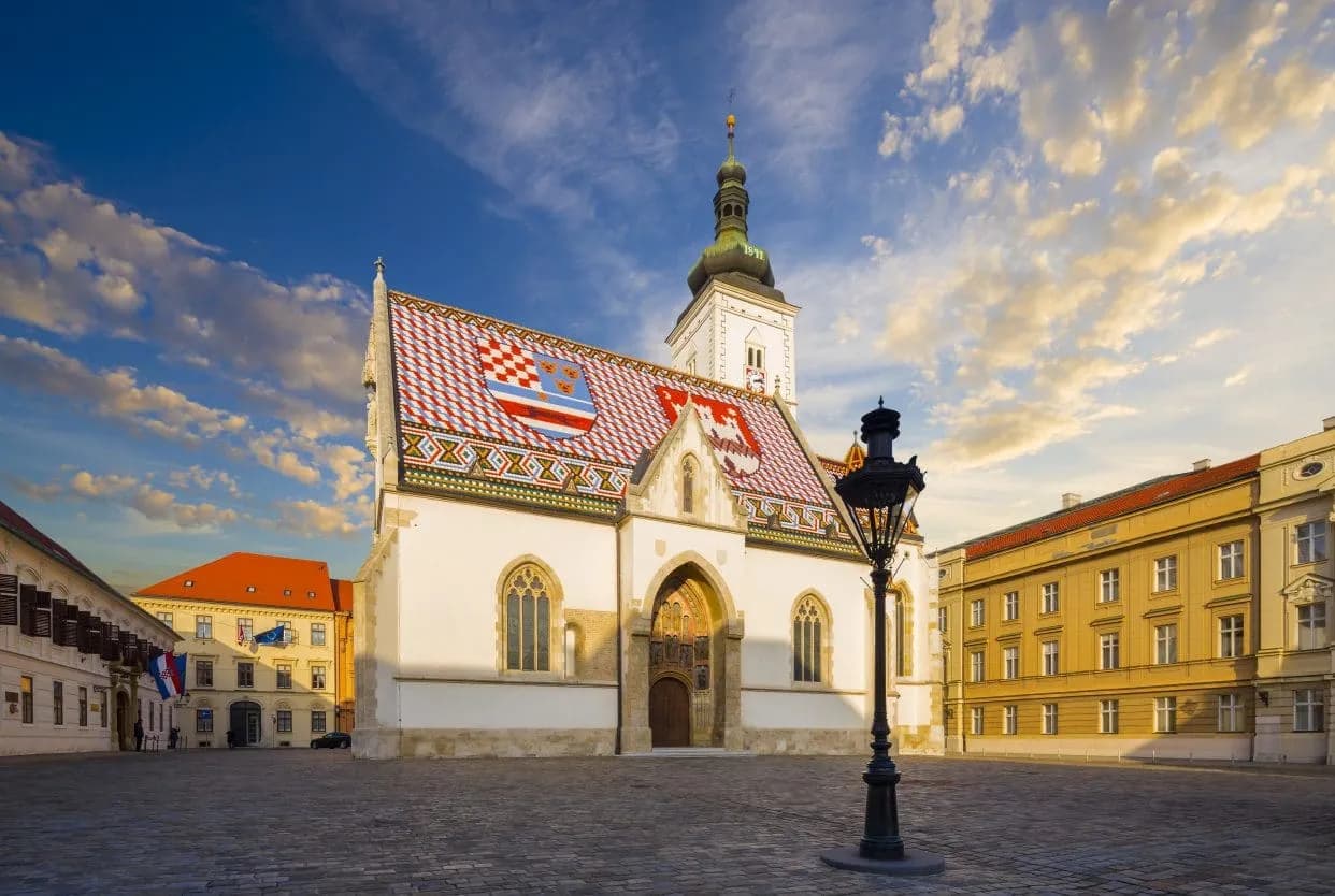 Church of St. Mark in Zagreb with colorful tiled roof and historic square at sunset.