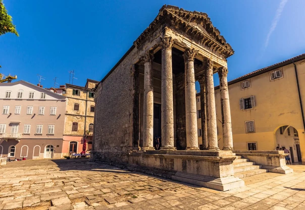 Roman Temple of Augustus with Corinthian columns in Pula, Croatia, under a clear blue sky.