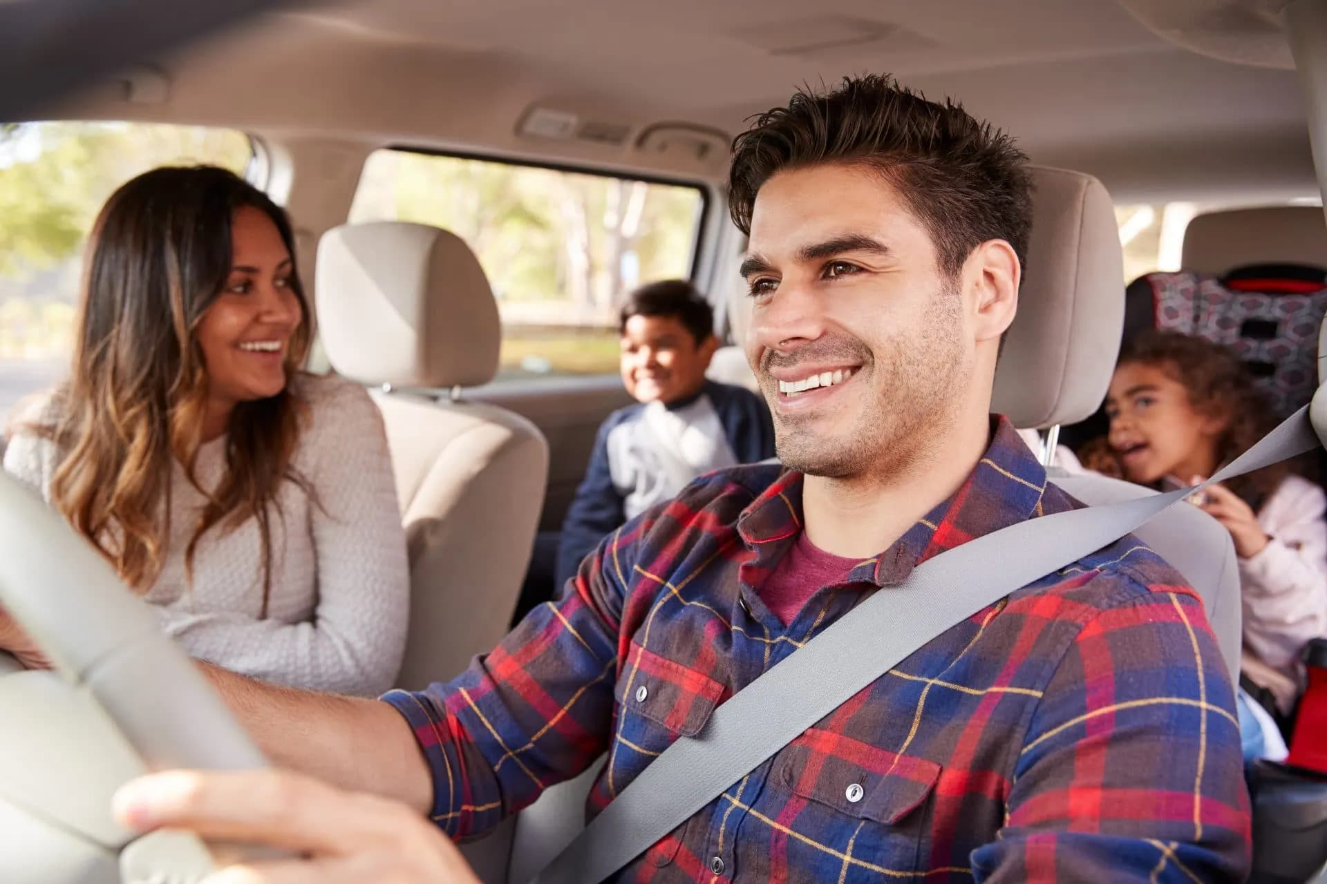 Family driving in car on self-guided holiday in Slovenia with trees visible outside.