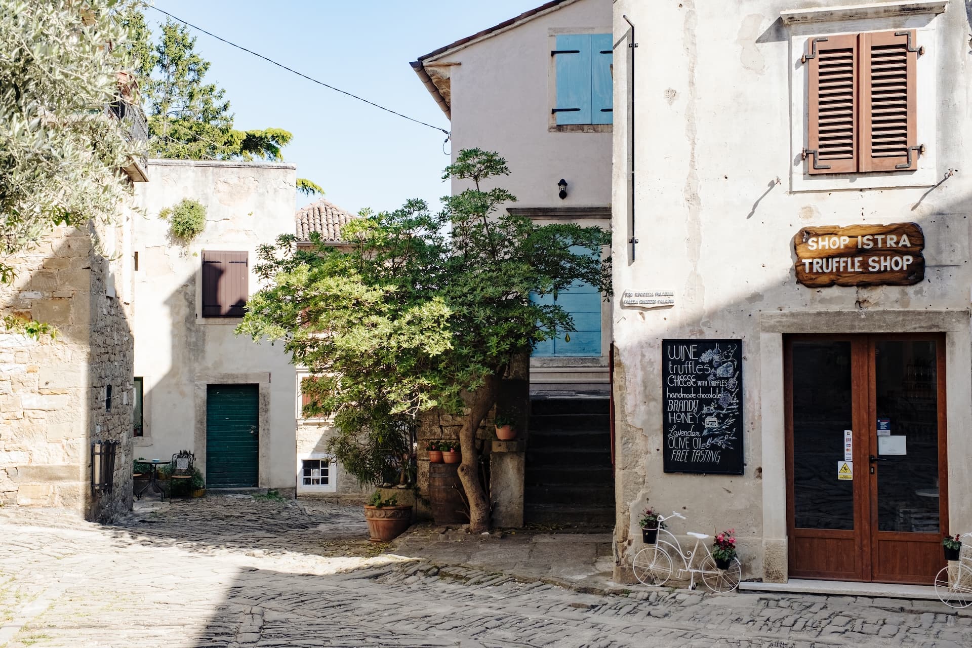 Cobblestone square in Grožnjan village, Istria, with a truffle shop and stone buildings.