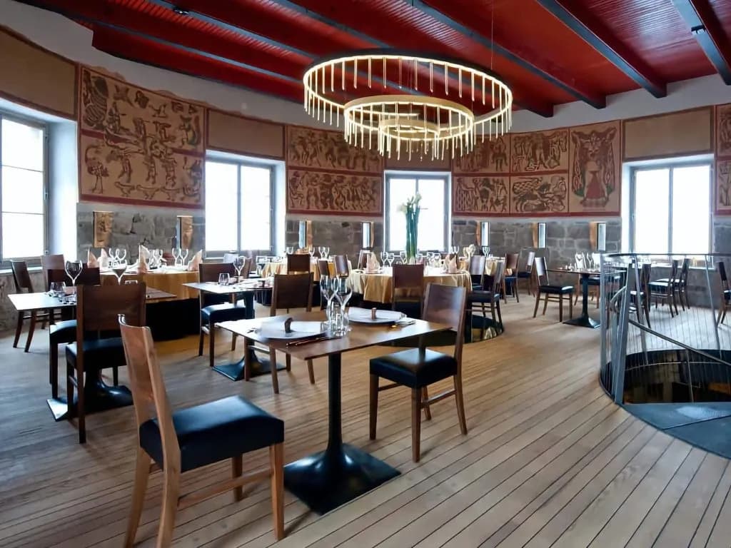 Restaurant dining room with stone walls, tapestries, and modern circular chandeliers